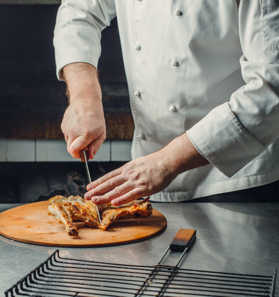 chef-cutting-grilled-chicken-wood-board-restaurant-kitchen
