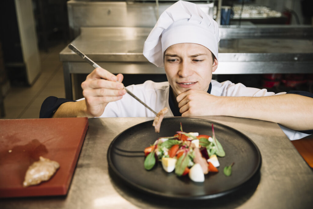 cook-preparing-salad-with-fried-meat-table