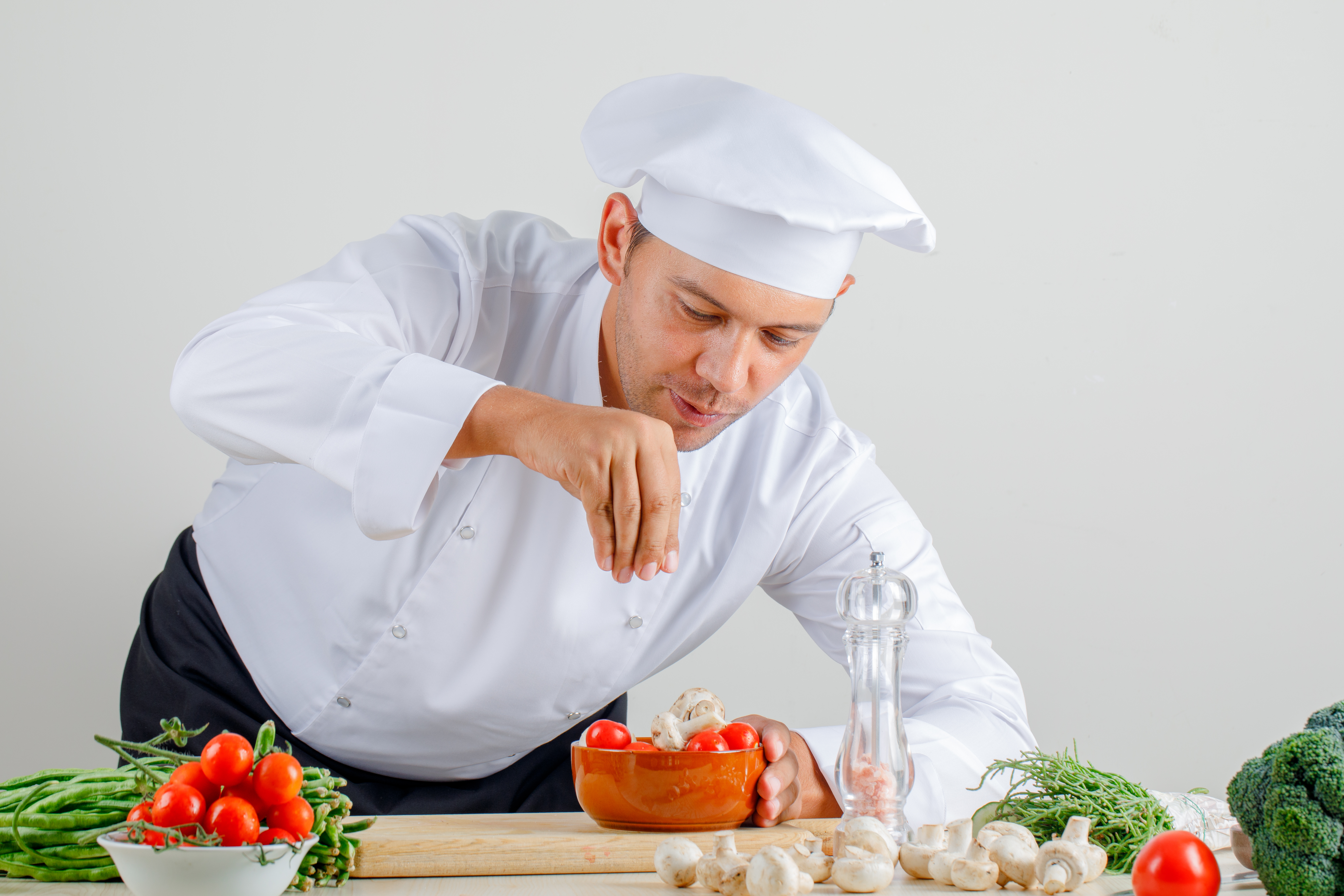 male-chef-uniform-hat-apron-adding-spice-into-food-kitchen