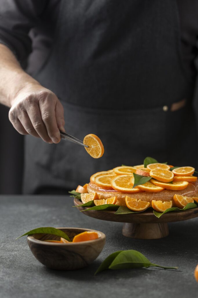 pastry-chef-putting-orange-slices-cake